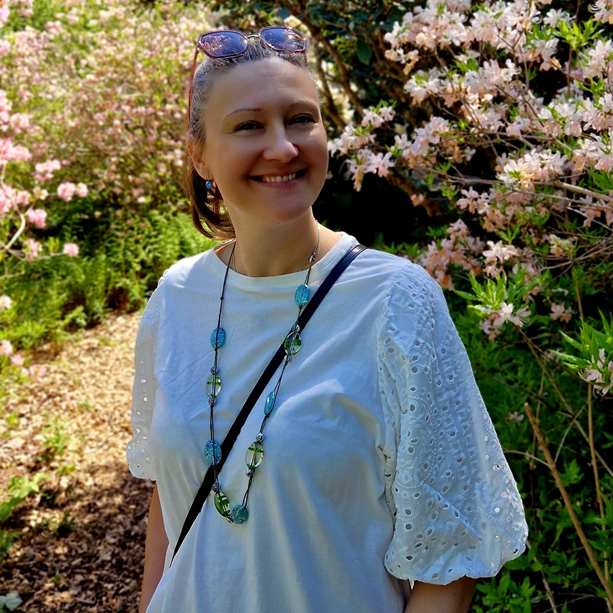 Adela smiling in a garden with pink flowering trees