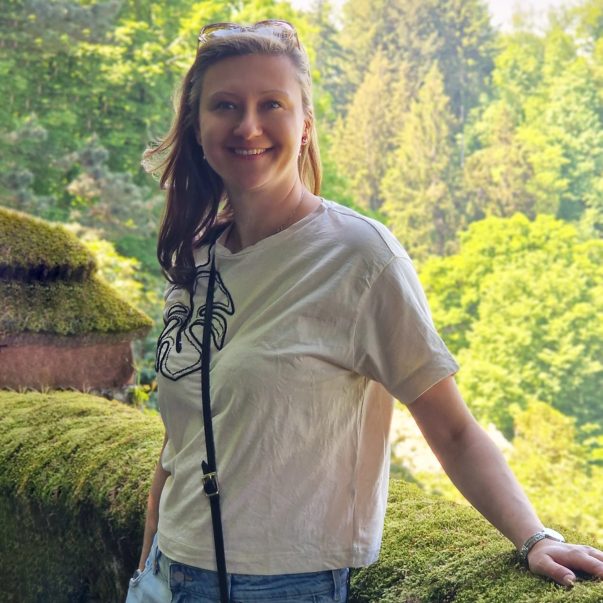 Adela Ganj smiling in a natural outdoor setting with green foliage background