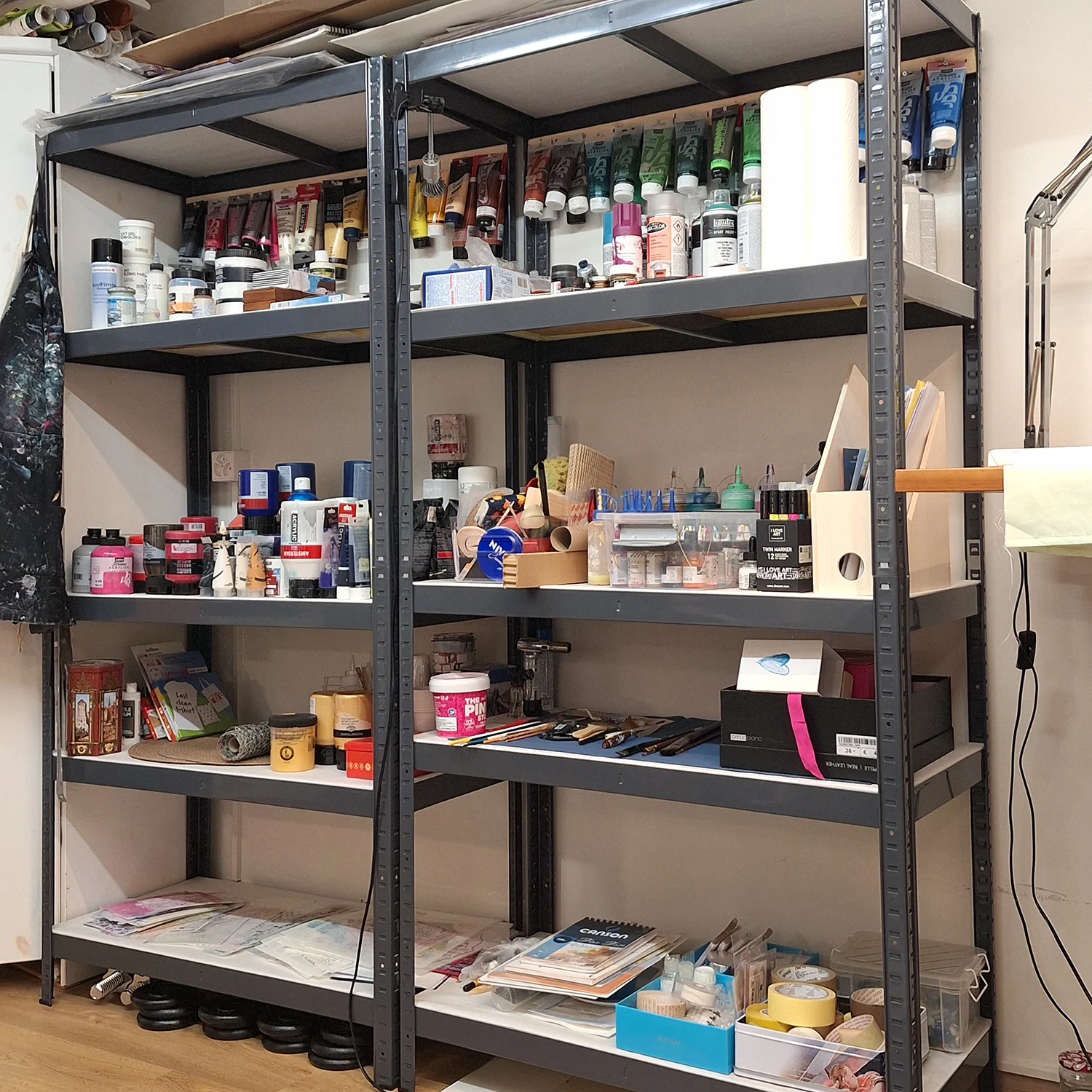Organized art studio with shelves of paints and art supplies
