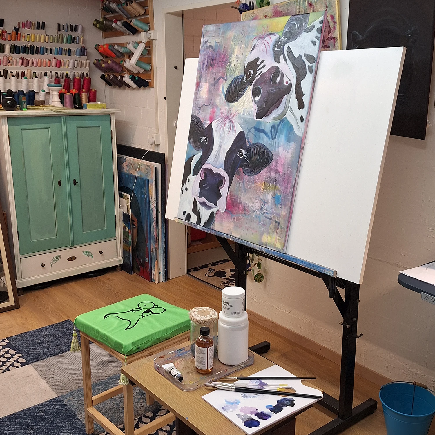 Art studio workspace with easel and colorful cow painting